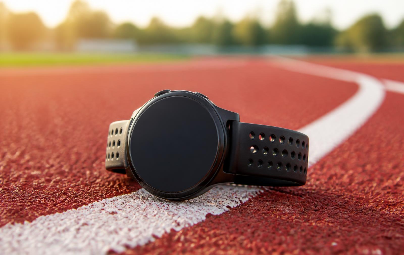 Zwart rond hardloophorloge met geperforeerd bandje op de witte lijn van een atletiekbaan